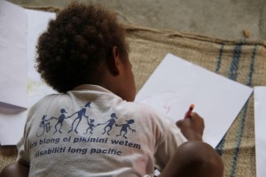 Boy from Vanuatu wearing project t-shirt and drawing a picture